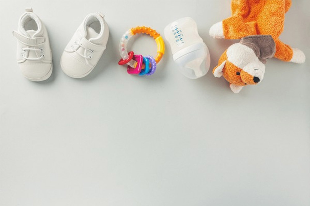 لوازم نوزاد شامل عروسک، شیشه شیر، جغجغه و پاپوش
